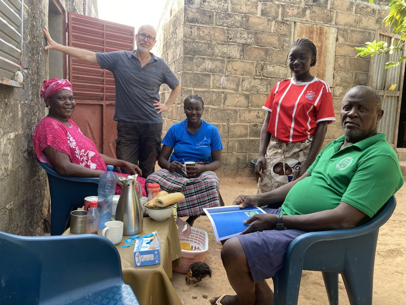 A host family sitting in the shade of their house