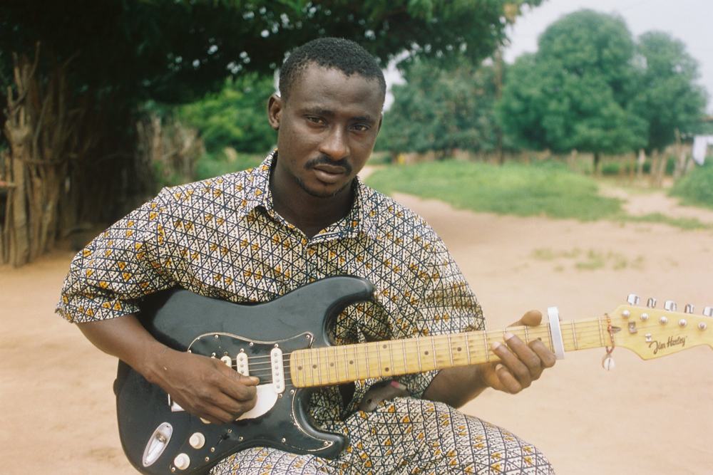 A man playing an electric guitar outdoors