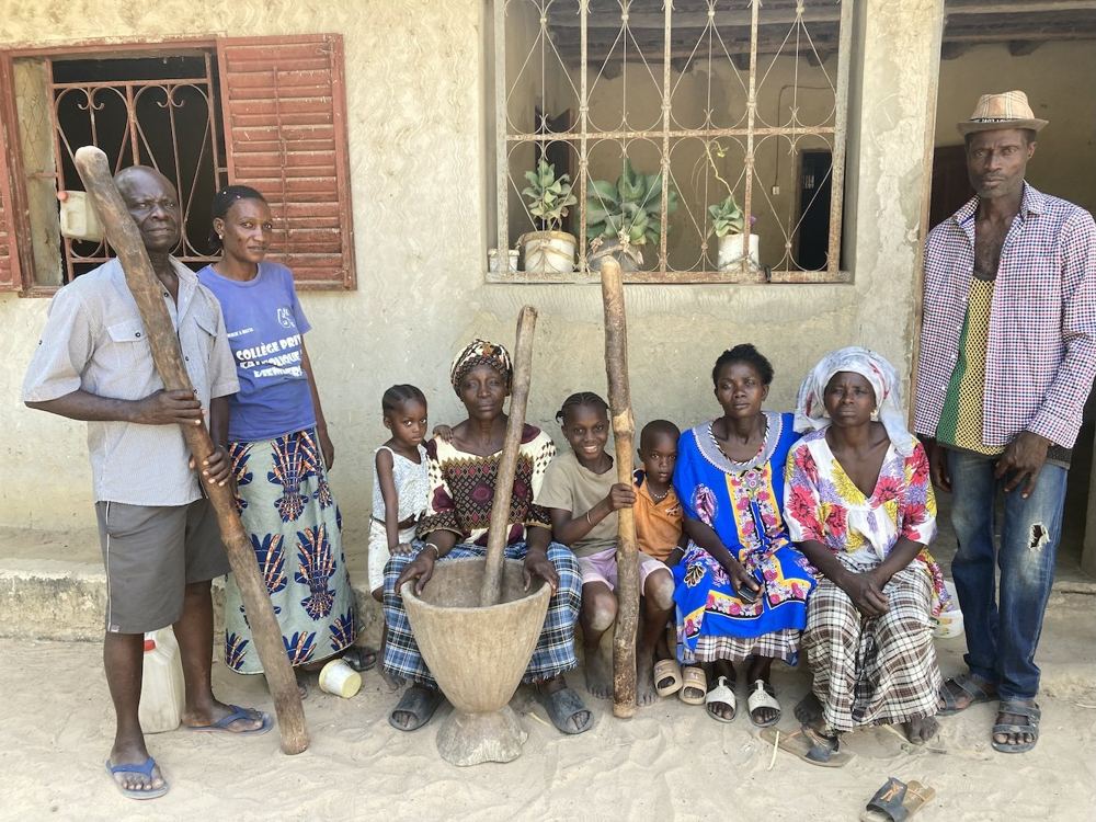 A family gathered in a courtyard, with wooden pestles for pounding grain